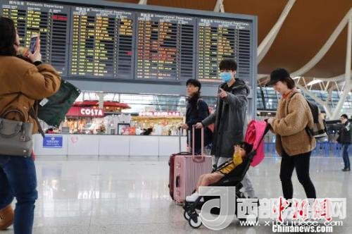 旅客帶著孩子前往辦票柜臺辦理登機手續(xù)?！∫罅⑶?攝