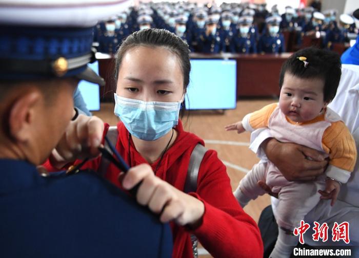 新消防員楊振的妻子彭莉與女兒現(xiàn)場見證丈夫加入“火焰藍(lán)”的神圣時刻?！⒅铱?攝