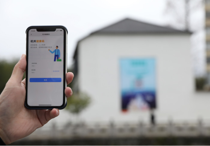 在浙江省杭州市臨安區(qū)天目山鎮(zhèn)，一名居民在“杭州健康碼”海報上掃碼申領(lǐng)個人二維碼。新華社發(fā)